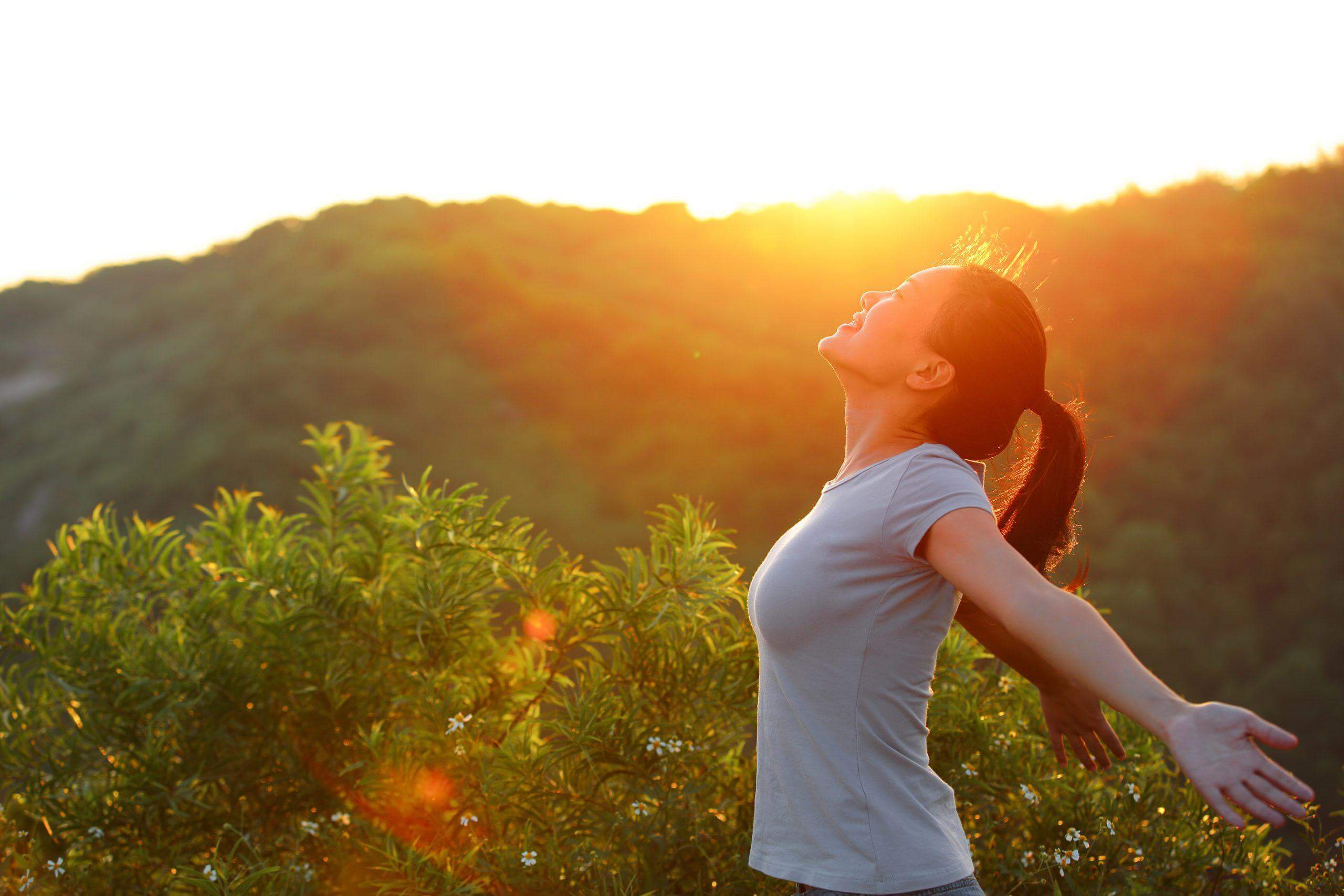 Woman spreading arms and enjoying sunlight outdoors